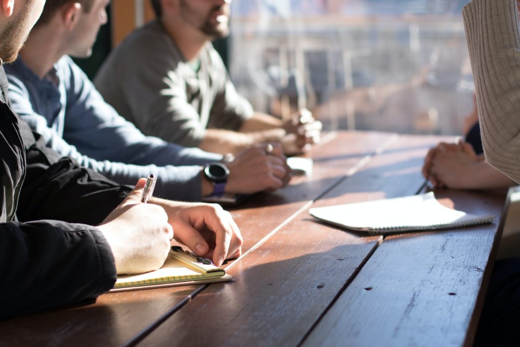 people discussing whilst writing notes on a table