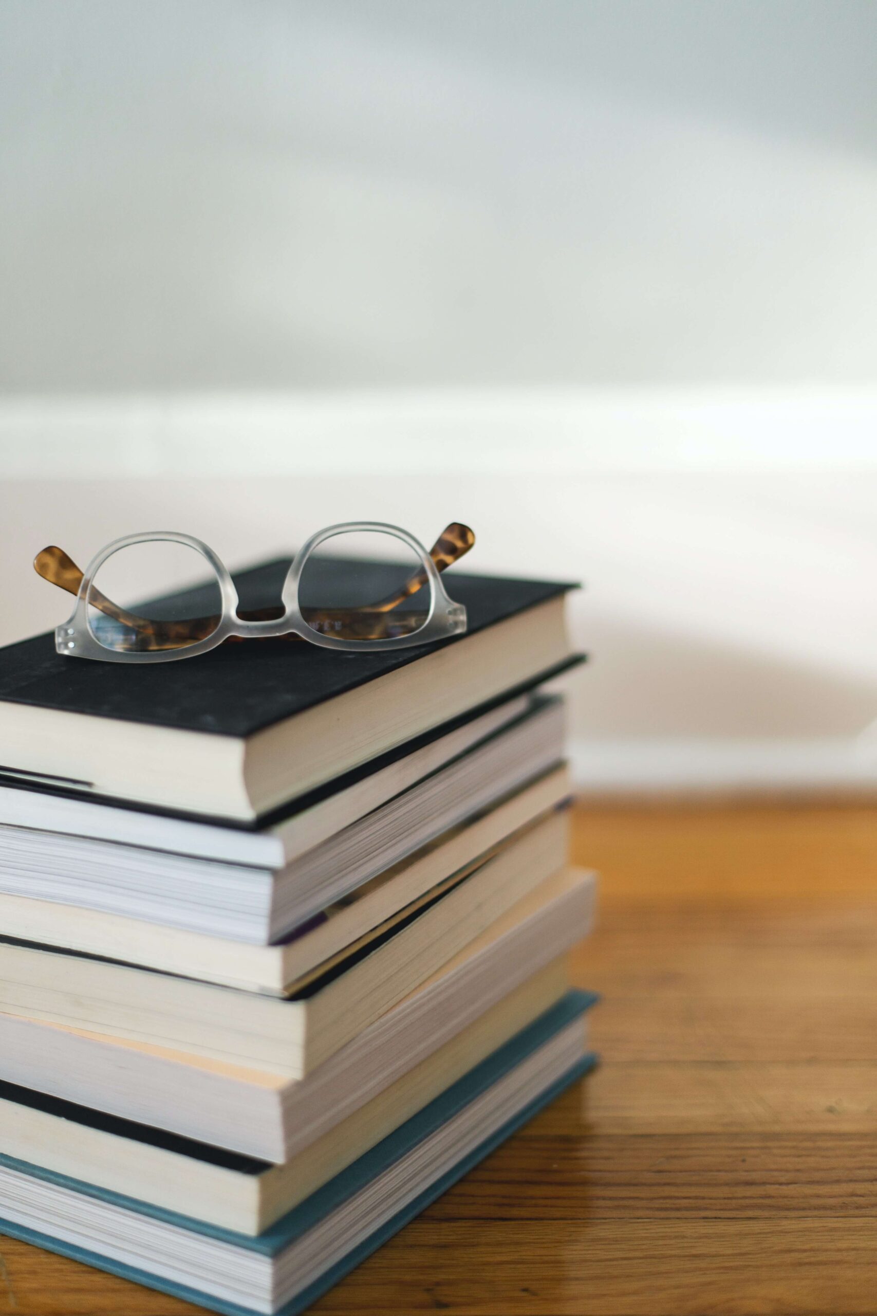 a pile of books with a pair of glasses on top